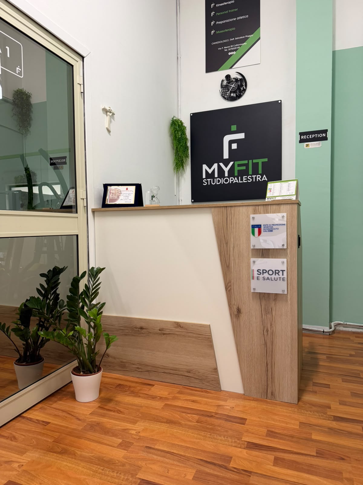Reception di MYFIT Studio Palestra con insegna e parete verde salvia